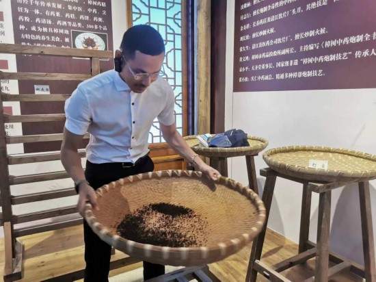 2023“一帶一路”媒體合作論壇聯合采訪團團員在非遺文化展示館體驗中藥炮制技藝。（本報記者黃超攝）