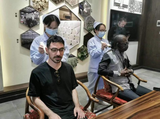 2023“一帶一路”媒體合作論壇聯合采訪團團員在九牛草展示館體驗艾灸。（本報記者黃超攝）
